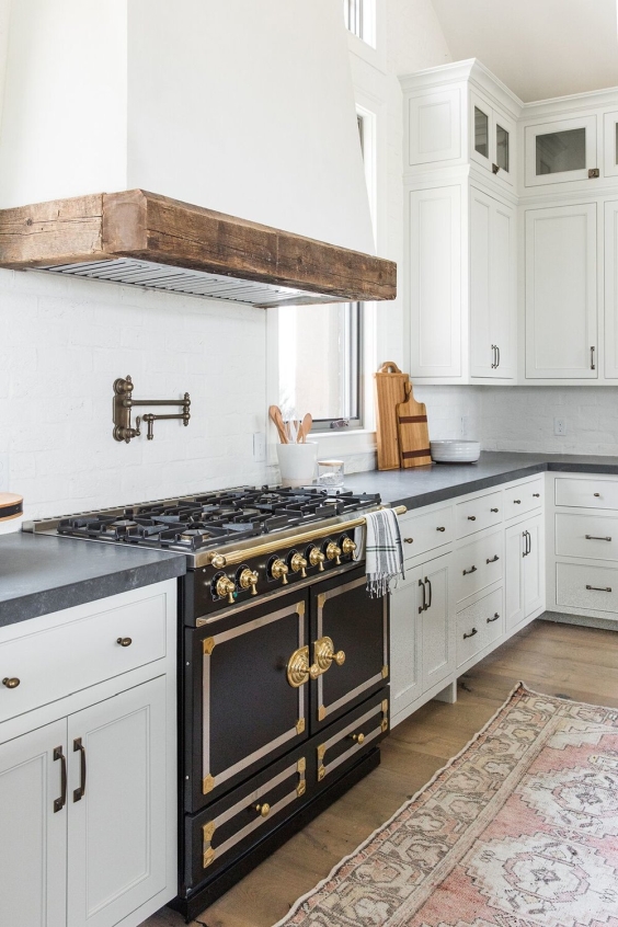 White kitchen unit with big black hob with golden accents