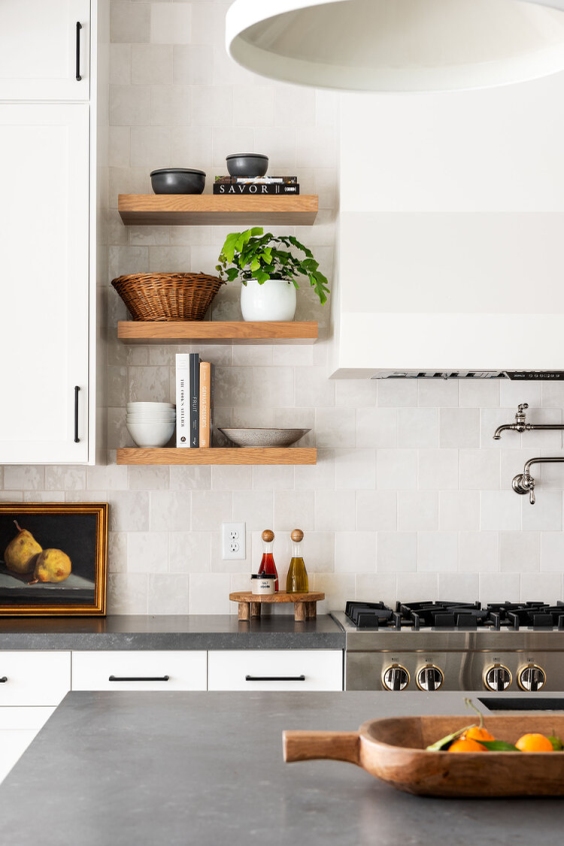 Colourful painting places on a black countertop in a white kitchen