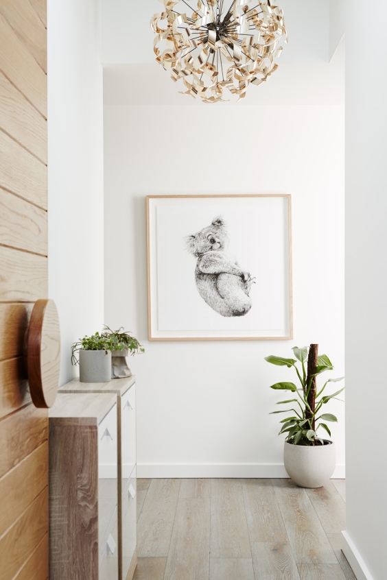 Picture in wooden frame on wall in all white hallway