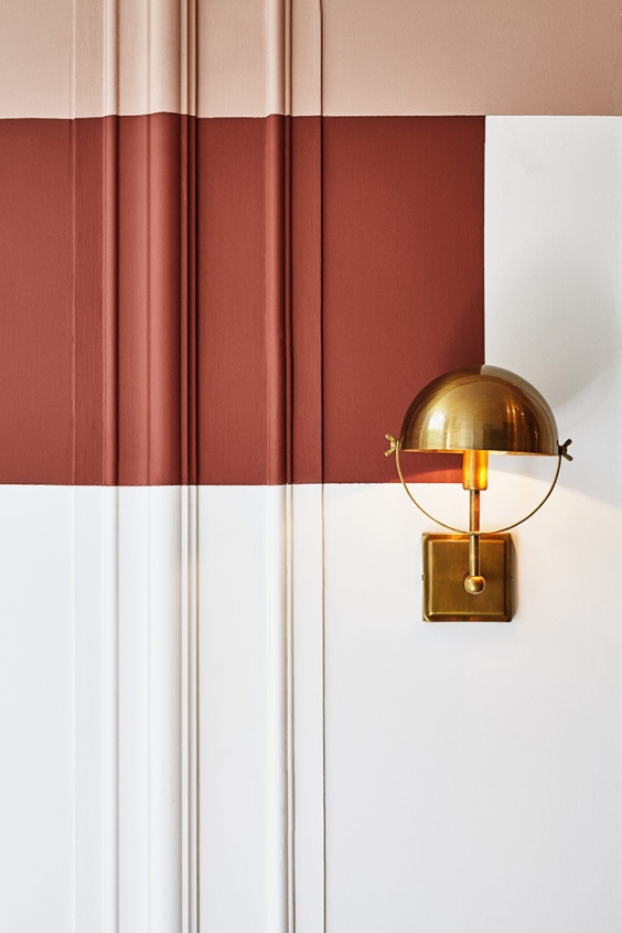 colourful wall in terracotta and white paint and golden wall lamp